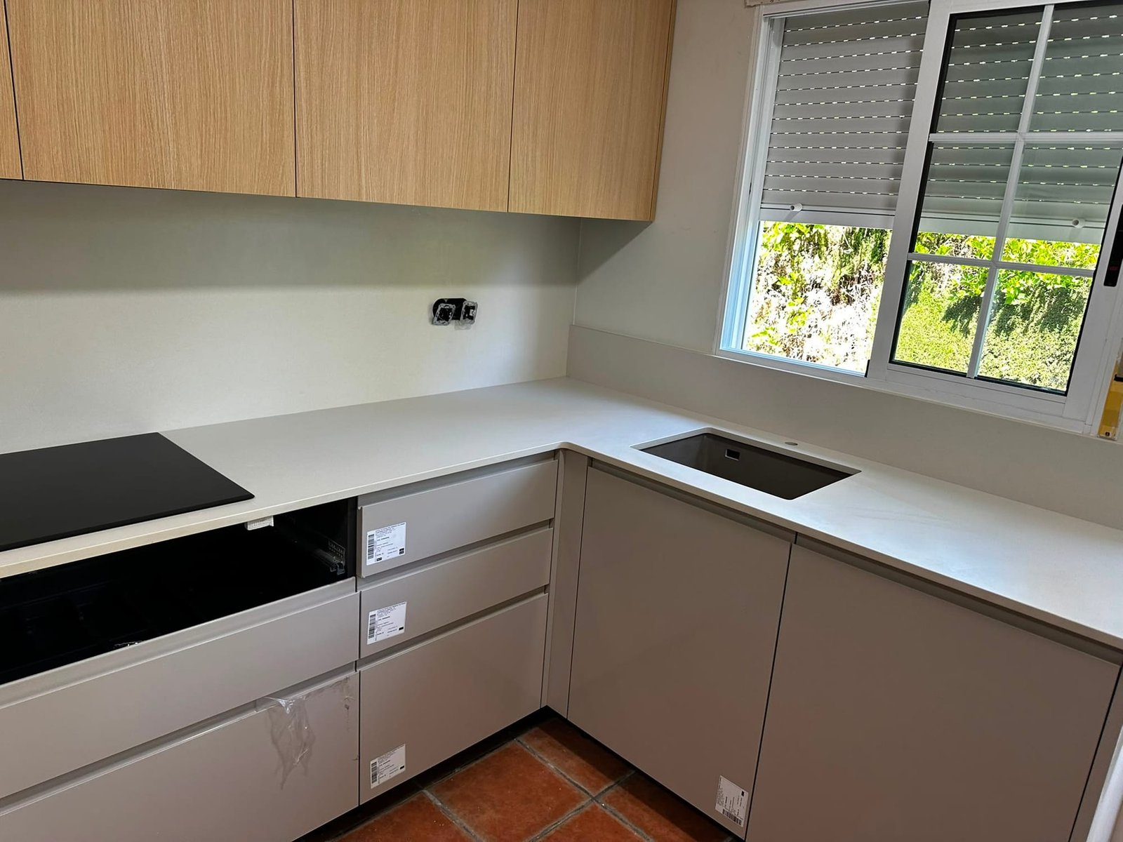 Cocina a medida con muebles altos en roble, bajos en gris y encimera blanca